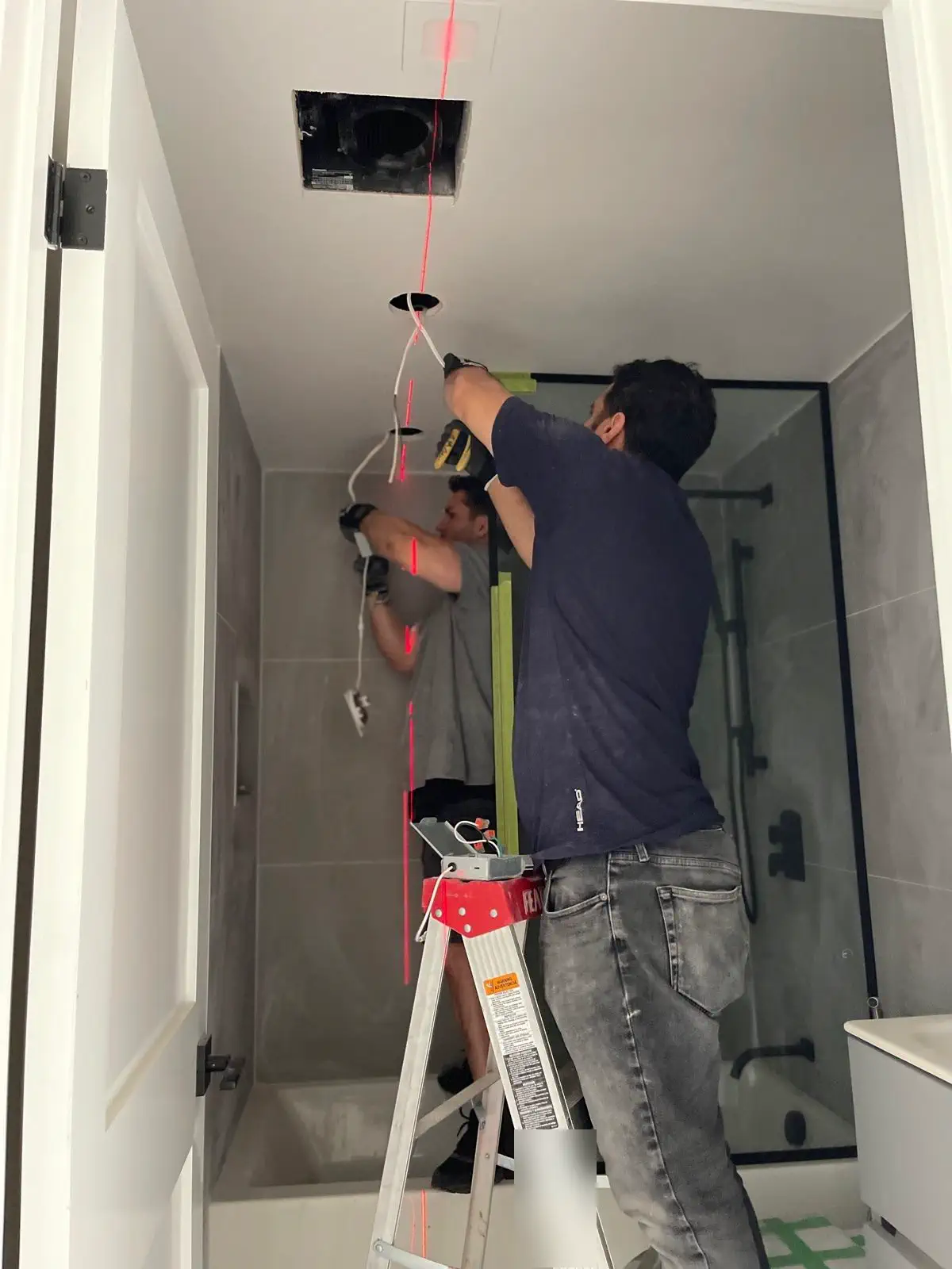 Two Shiraz Electric technicians installing pot lights in a bathroom ceiling in Thornhill